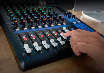 Closeup hand raise volume on sound mixer panel. Musician producing music in professional recording studio.