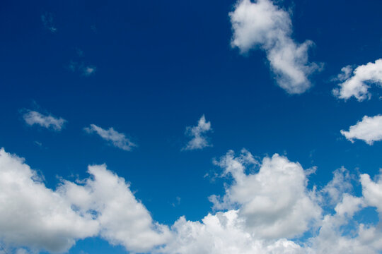 Blue, bright sky background with white clouds clouds.