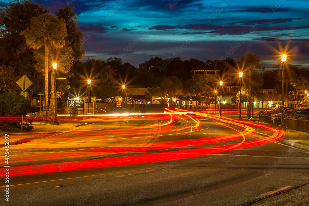 Poster Closeup shot of illuminated town and long exposure car lights on the roads in the evening