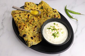 A Food called Methi paratha or Methi thepla is an Indian breakfast dish served with curd and a...
