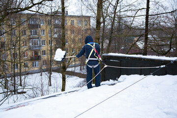 City service remove snow from roof of a building. A man in overalls cleans the roof from snow with...
