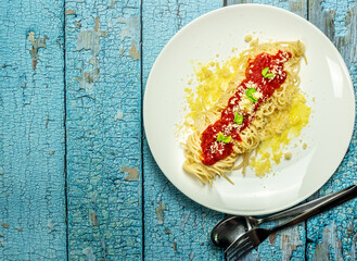 Delicious classic homemade spaghetti al pomodoro with a beautiful summer tomatoes. Served with parmesan cheese and fresh basil. Presented with copy space, top view.
