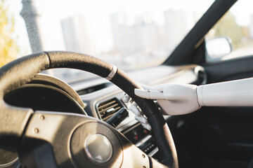 artificial robotic white arm holding steering wheel and driving vehicle