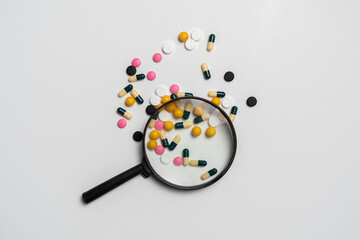 creative pharmacy and health layout, magnifying glass on top of medicine pills tablets and capsules