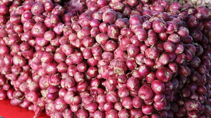 Pile of red onion on tray. Raw red onion background on a stall with natural light in a Thai local market. selective focus
