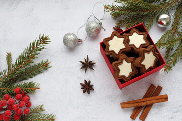 Christmas background with star shaped cookies in red gift box, fir tree branches and christmas decorations. Flat lay festive composition. Top view