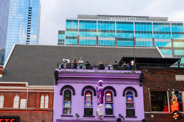 a shot of a purple rooftop bar in the cityscape with people standing near the edge in Nashville...