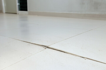 Ceramic tiles floor cracked and broken from concrete inflate in house or office building. Floor...