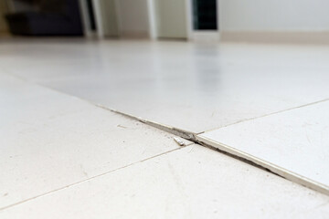 Ceramic tiles floor cracked and broken from concrete inflate in house or office building. Floor...