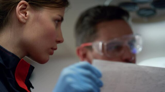 Portrait of serious paramedics looking at electrocardiogram graphs on paper