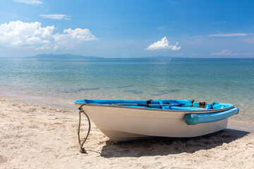 Fishing boat on the white sand beach against blue sky and sea in Thailand.