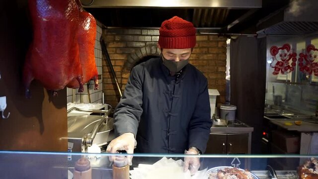 vendor preparing the wrap for the peking duck wrap in street food market in Beijing, China