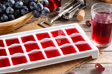 Wine in ice cube tray on a wooden table. Frozen wine