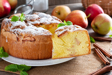 Clasic sponge cake with apples on wooden table. Homemade cake