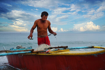 TRADITIONAL FISHERMAN PREPARING HIS NET. ANINUAN BEACH, ORIENTAL MINDORO, PHILIPPINES 2021 