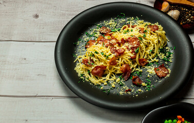 Spaghetti alla carbonara, This is a traditional Italian recipe for a quick dinner which consists of bacon, eggs, olive oil, basil and cheese.  Horizontal view from above and copy space.