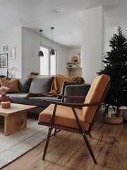 Modern interior design with Christmas tree. Winter holidays composition. Elegant living room with comfortable sofa, mid-century modern lounge chair, cozy carpet, wooden coffee table