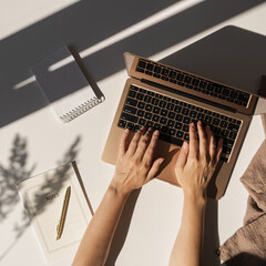 Flatlay of person hands working on laptop computer. Aesthetic bohemian home office workspace. Work...