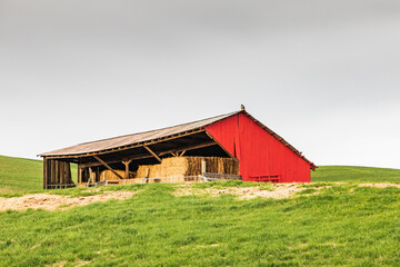 Obraz premium Steptoe, Washington State, USA. A red hay shed in the Palouse hills of Washington. (Editorial Use Only)