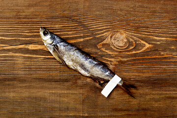 Jerked salted Baltic herring with paper label on tail on wooden table