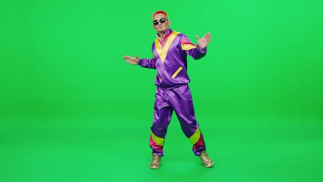 Pretentious retro guy in a purple suit dancing to the music on a green background, young digital influencer creates content, chromakey template, 4k slow motion.