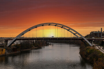 Fototapeta na wymiar a stunning shot of the Cumberland River with bridges over the river and gorgeous autumn trees with powerful clouds at sunset in Nashville Tennessee USA