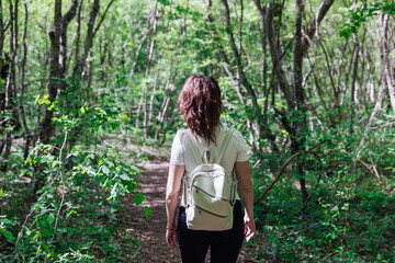 woman traveler in green forest hiking adventure