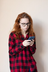 young red-haired girl talking on the phone on a light background