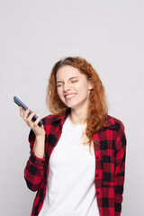 Fototapeta premium girl in a plaid shirt on a light background with a smartphone