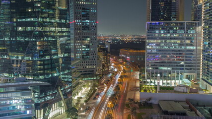 Fototapeta na wymiar Traffic on a road in Dubai International Financial district aerial night timelapse. Panoramic view of business and financial office towers.
