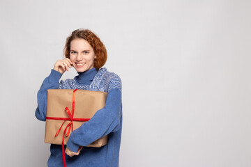 young girl in a sweater is holding a gift on a white background