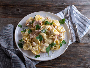 Tortellini alla panna. Traditional italian pasta dish with ham, cream sauce, parsley and parmesan cheese