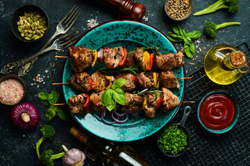 Fototapeta na wymiar Kebabs - grilled meat skewers, shish kebab with vegetables on a plate. On a concrete old table. Top view.