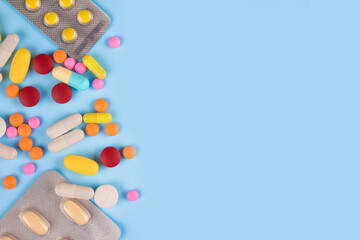 Assorted multicolored medicine pills, capsules and tablets on blue background with copy space. Immune system vitamins and supplemets. Dietary bio supplements