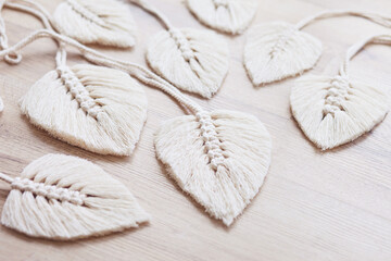 Macrame leaves in natural color on the wooden background. Cotton rope decor macrame to make your home more cozy and unique. Woman hobby.