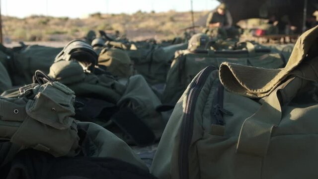 Close-up of military bags and military equipment lying in the sun in the middle of the desert