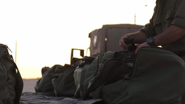 Close-up of soldiers hands prepare his equipment in his military bag ready to war at the sunset