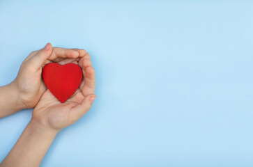 Fototapeta premium a small heart in children's hands on a blue background