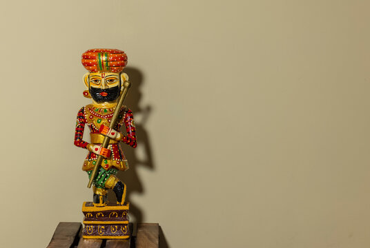 Handmade colorful wooden Rajasthani Doorkeeper or guard souvenir standing with plain background.