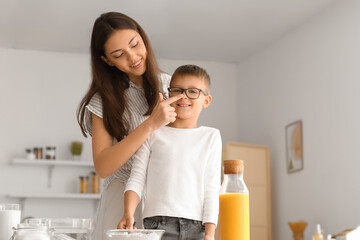 Teenage girl touching nose of her little brother in kitchen