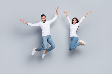 Full size photo of nice young brunet couple jump wear white shirt jeans footwear isolated on grey...