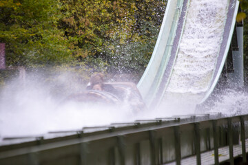 Extreme water flume ride in the amusement park with green trees in the background