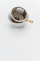 metal tea strainer in a white stoneware bowl on a white tabletop