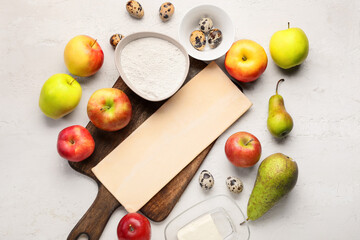 Board with fresh dough and ingredients for apple strudel on white background