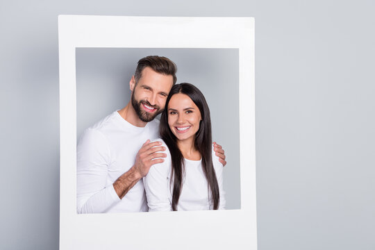 Portrait of attractive adorable cheerful couple hugging enjoying in photo frame isolated over grey pastel color background