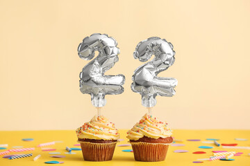 Tasty Birthday cupcakes with number 22 on color background
