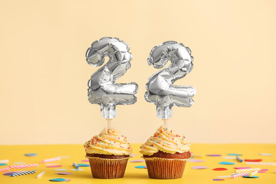 Tasty Birthday cupcakes with number 22 on color background