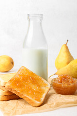 Bread with tasty pear jam and bottle of milk on table