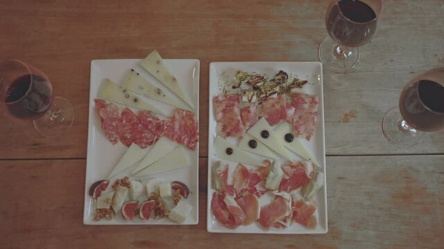 top view of hands picking food from the dish on wooden table with  glass of wine - aperitif time - happy hour concept