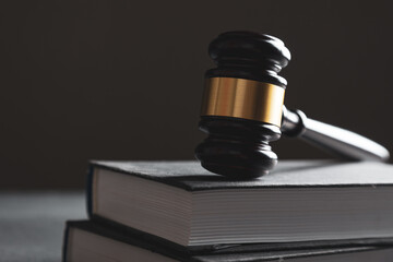 Law theme, judge gavel on a dark table with a book.